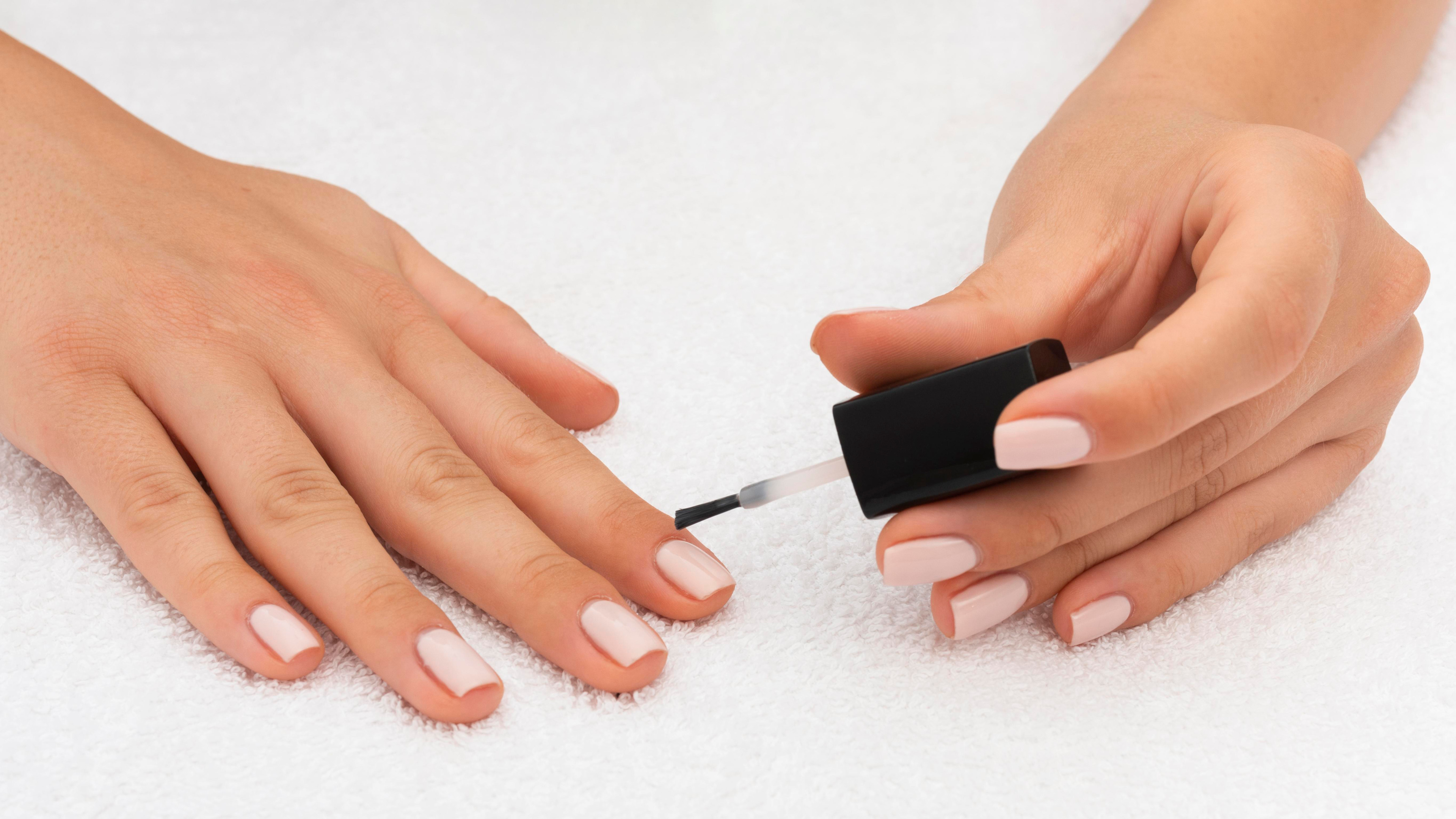 A woman applying gel nail polish on her nails 